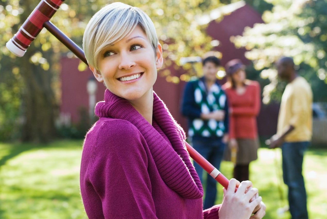 Young woman with croquet mallet to illustrate the many lawn games for your backyard