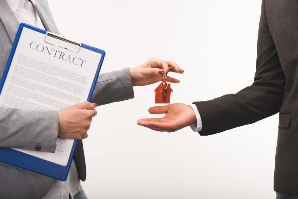 Real Estate Agent holding a contract and giving a client the keys to their new home