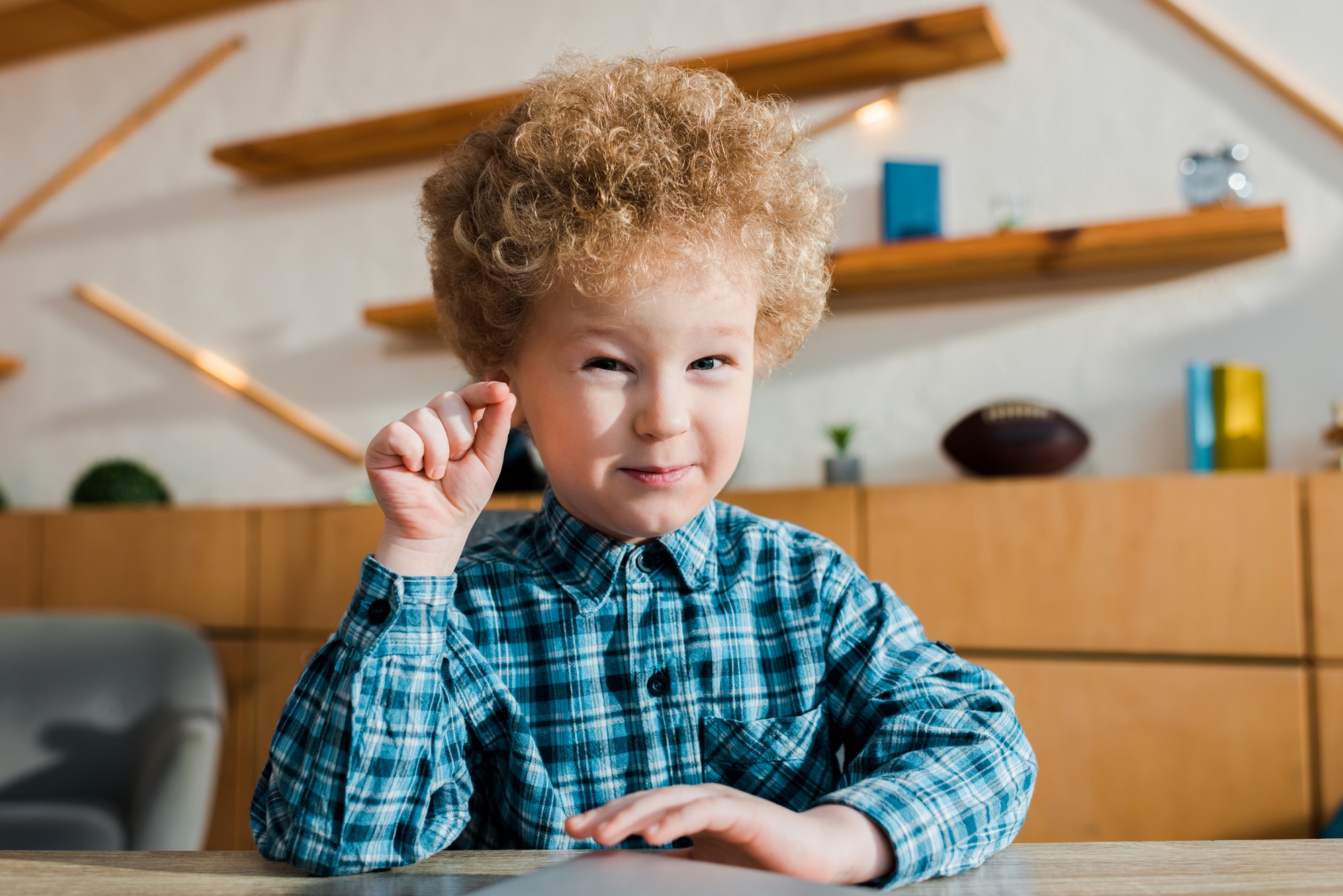 Toddler in a home learning space with shelves behind him