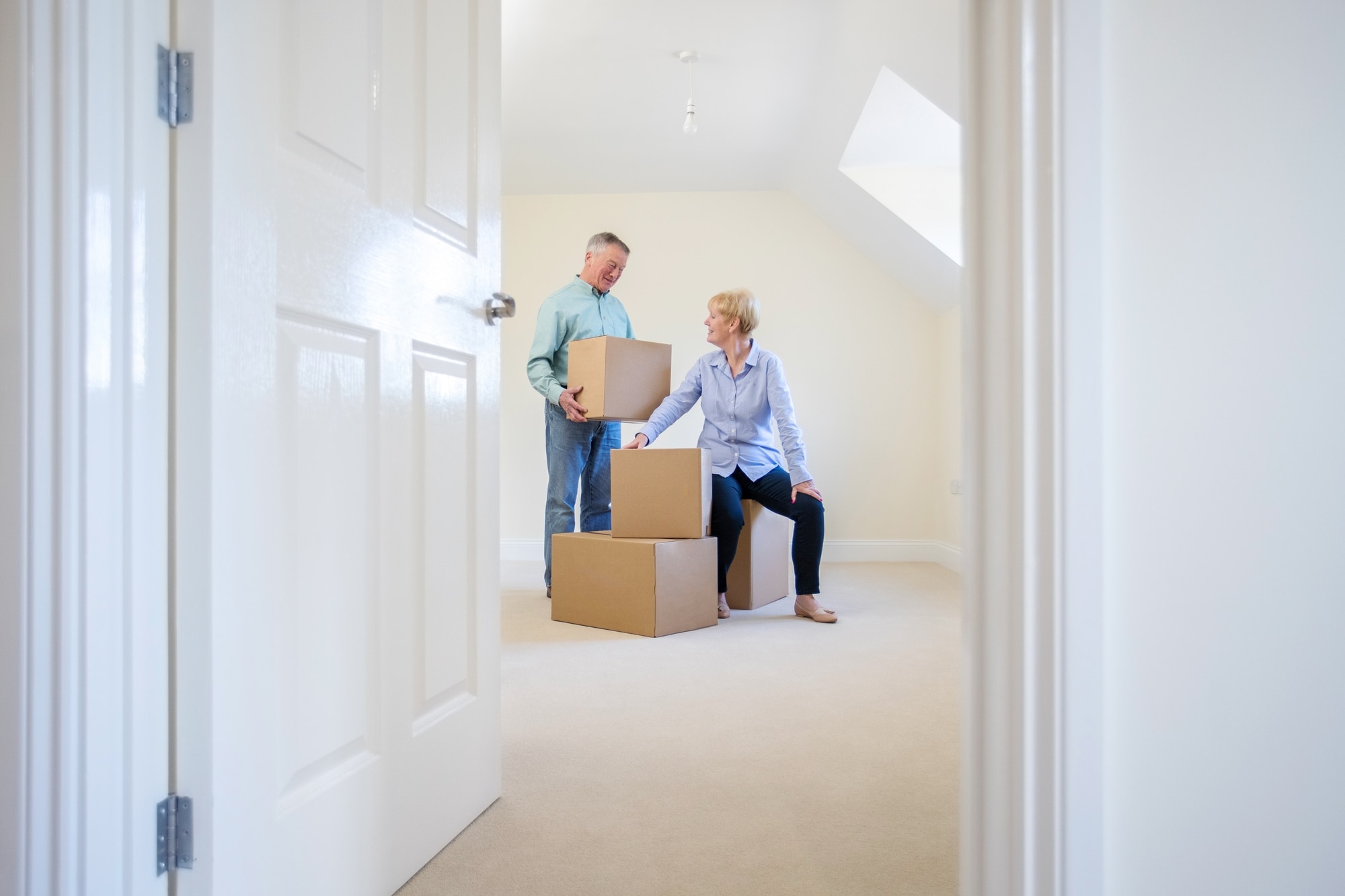 Senior couple  moving -- sitting with boxes in an empty room