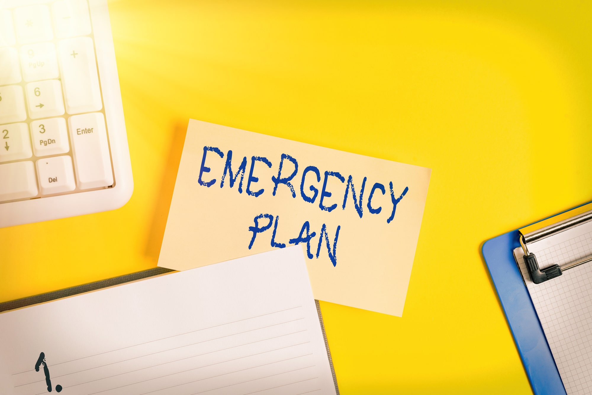 Writing note showing Emergency Plan. Business concept for procedures for handling sudden or unexpected situations Empty orange paper with copy space on the yellow table