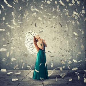 Excited young woman with umbrella under a money rain isolated on grey wall background. Positive emotions financial success luck good economy build wealth