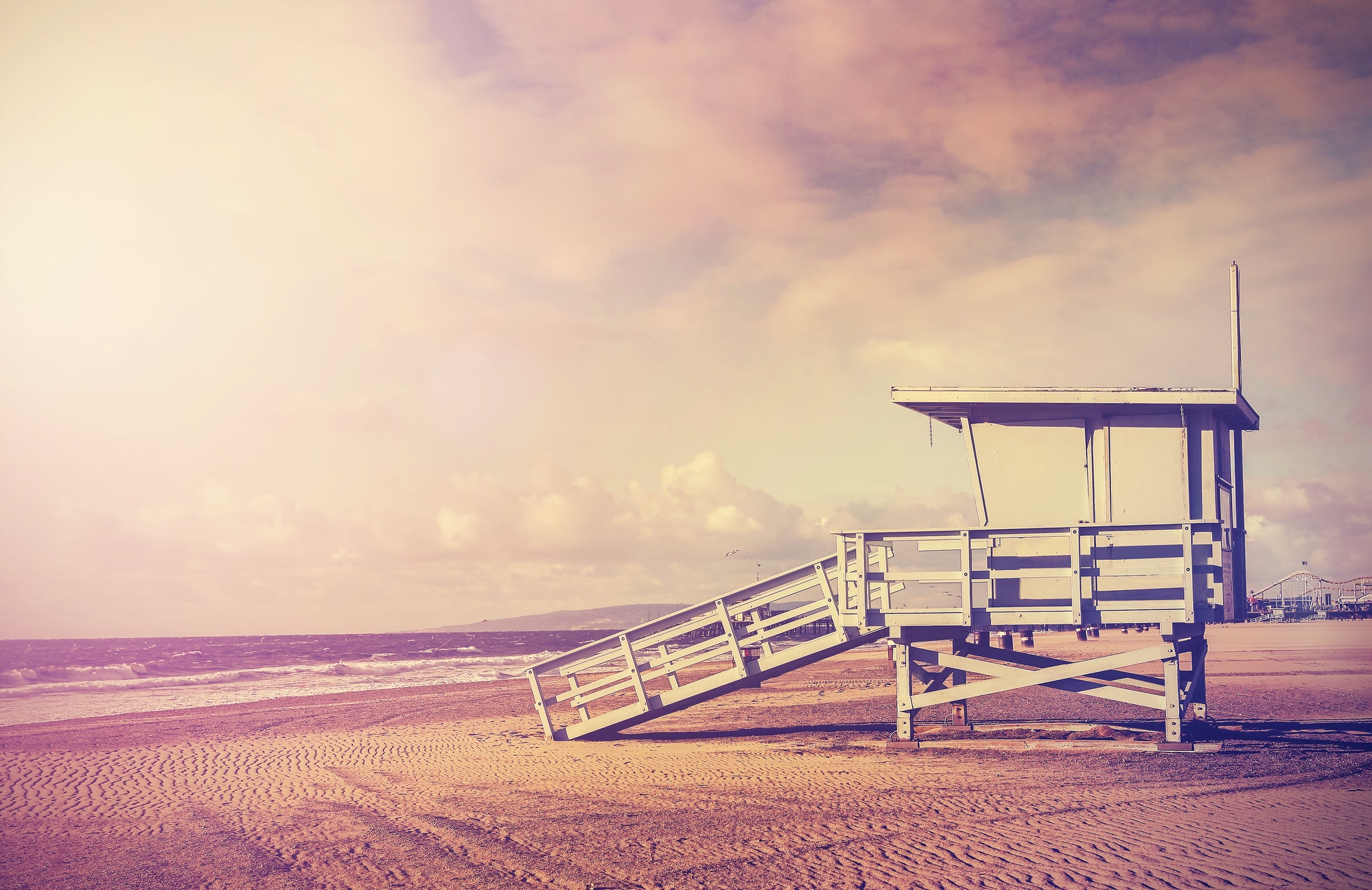 Vintage filtered picture of wooden lifeguard tower at sunset, beach in California, USA.