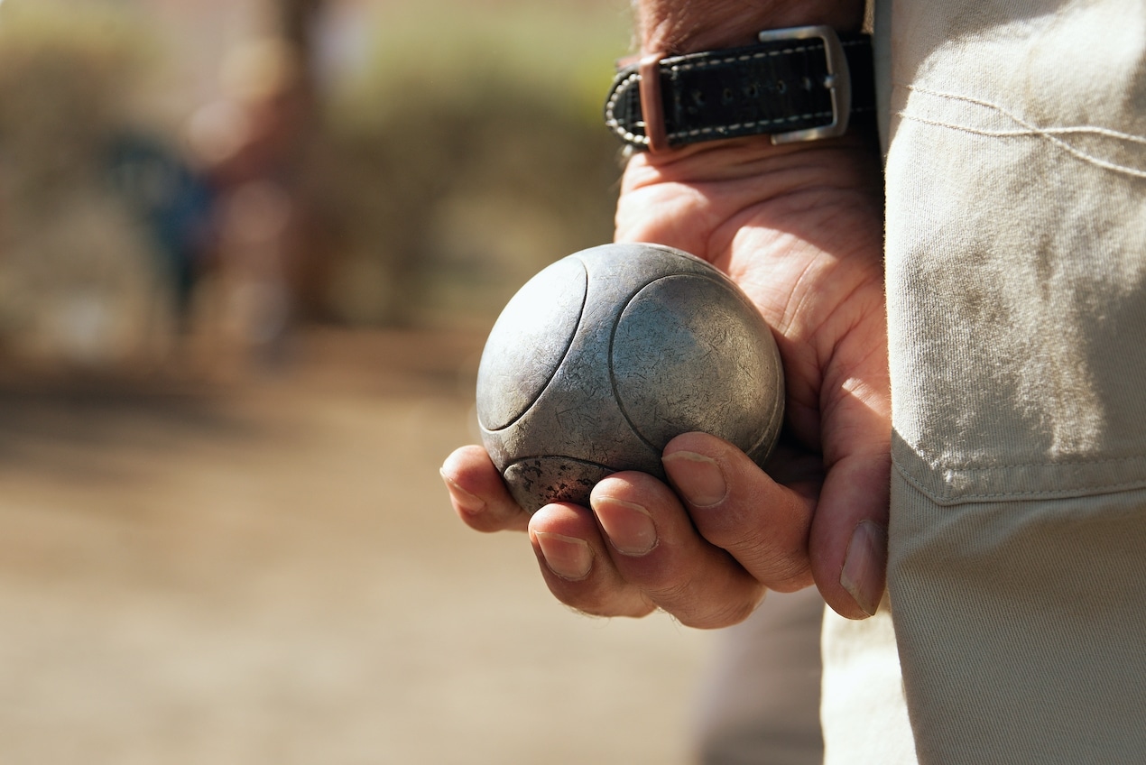 Man with Bocce ball in his hand ready to throw it in the backyard