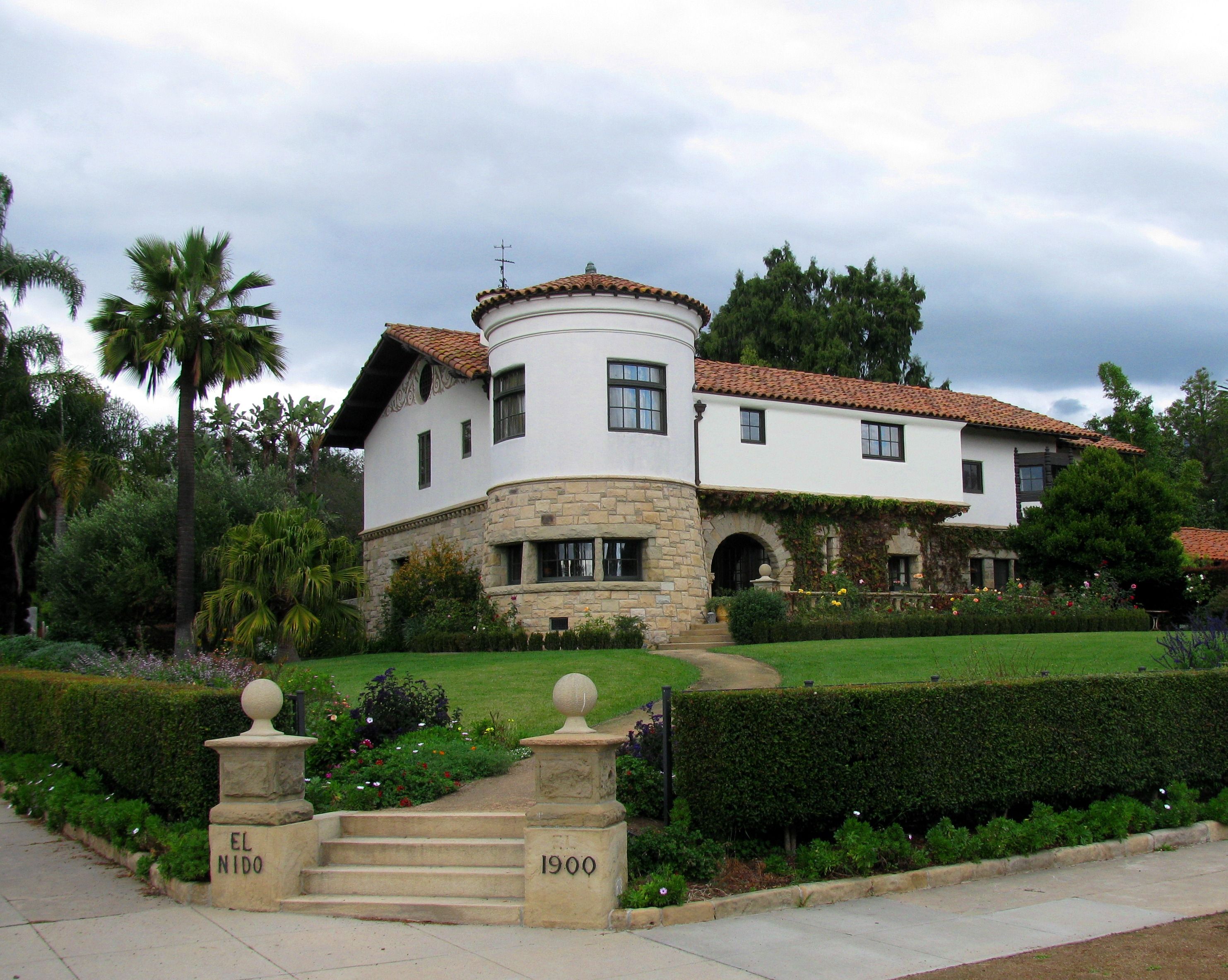 The Santa Barbara landmark residence known as the Charles H. Hopkins Home, with stone pillars and a hedge leading to a lush lawn, and the two-story home with its large turret