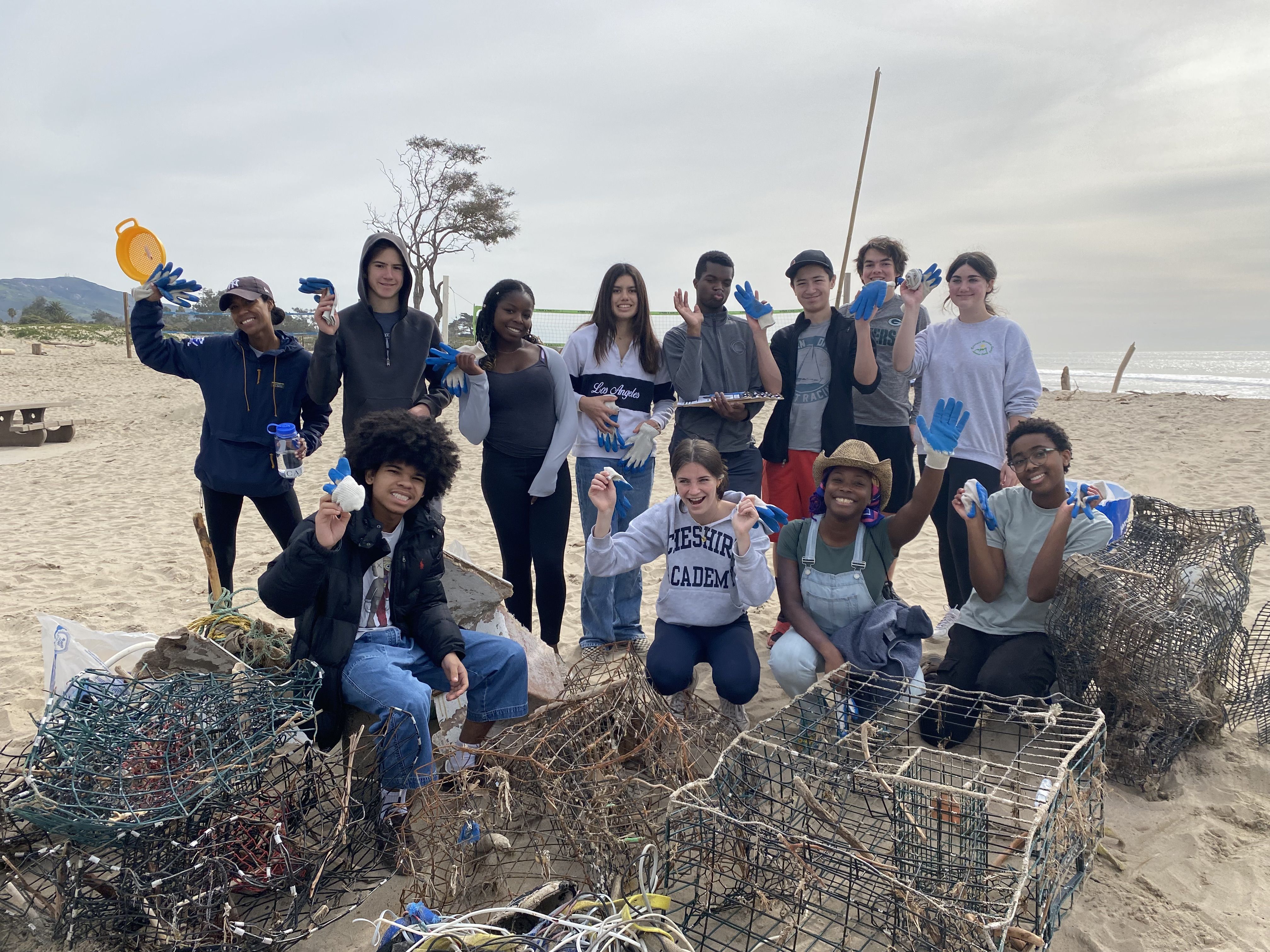 A group of young volunteers posing with trash on the beach