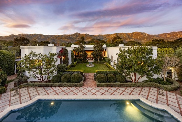 The backyard of a luxury home with a serene pool and lovely landscaping.
