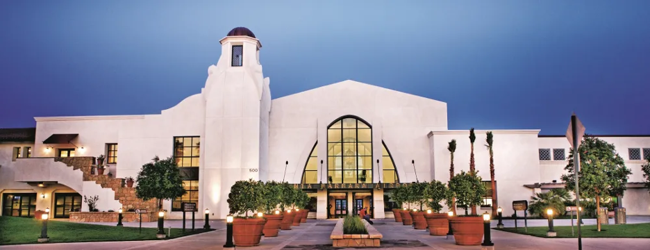 An image of the front of the Santa Barbara Airport with the tidy landscaping and a blue sky.