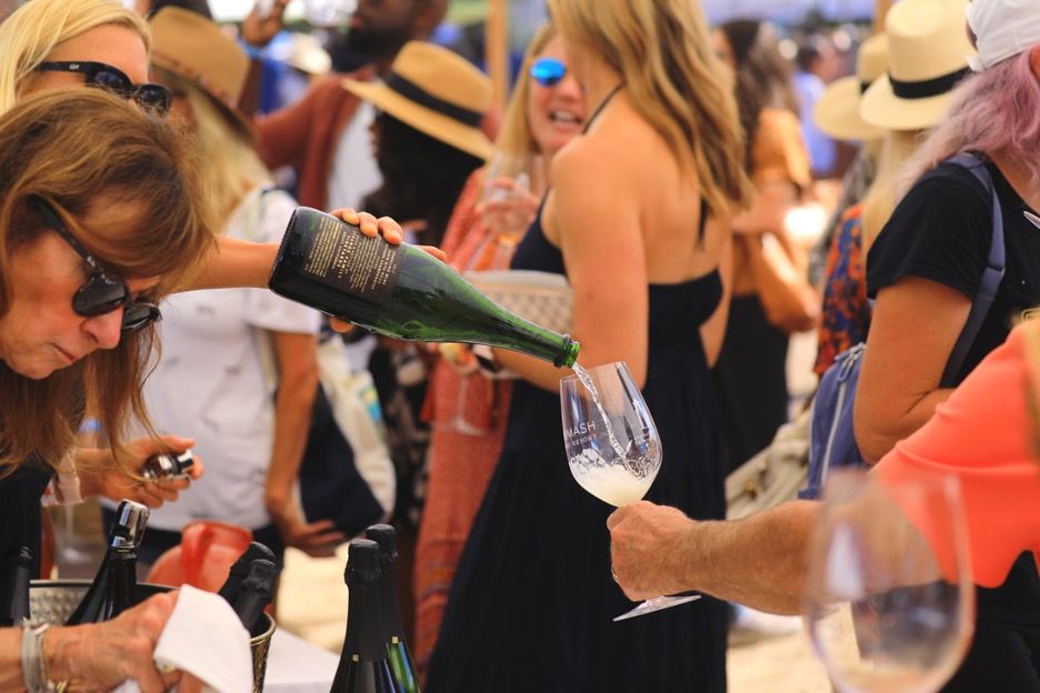 A crowd at the annual Santa Barbara Vintner's Festival with wine being poured into someone's glass