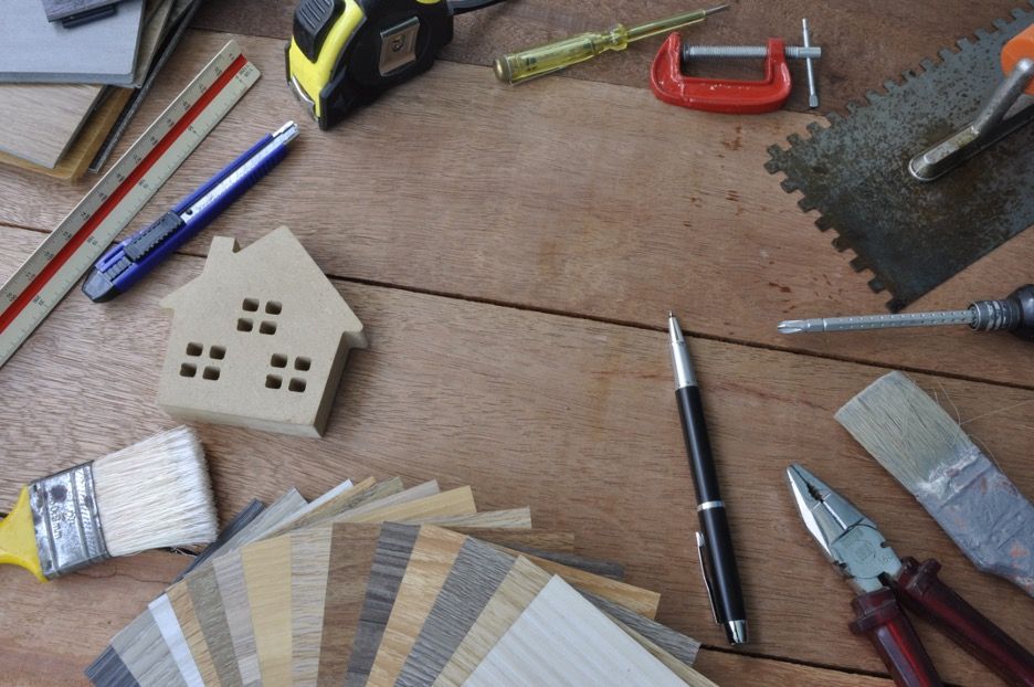 Image of home improvement materials including a pen, a paintbrush and some flooring samples.