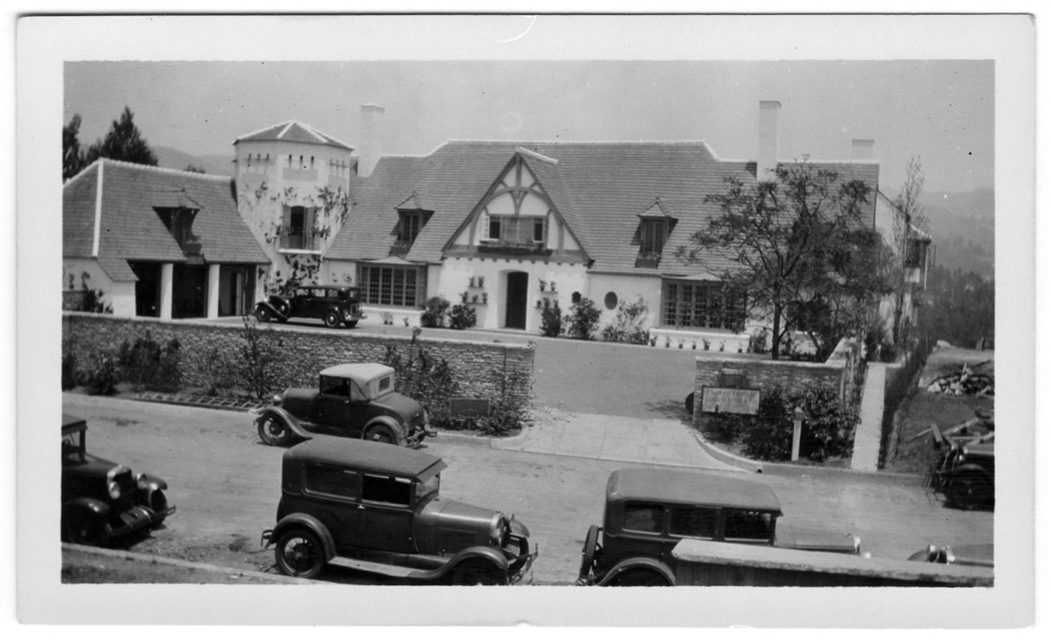 A vintage black and white photograph of Pickfair, with automobiles from the golden age in front