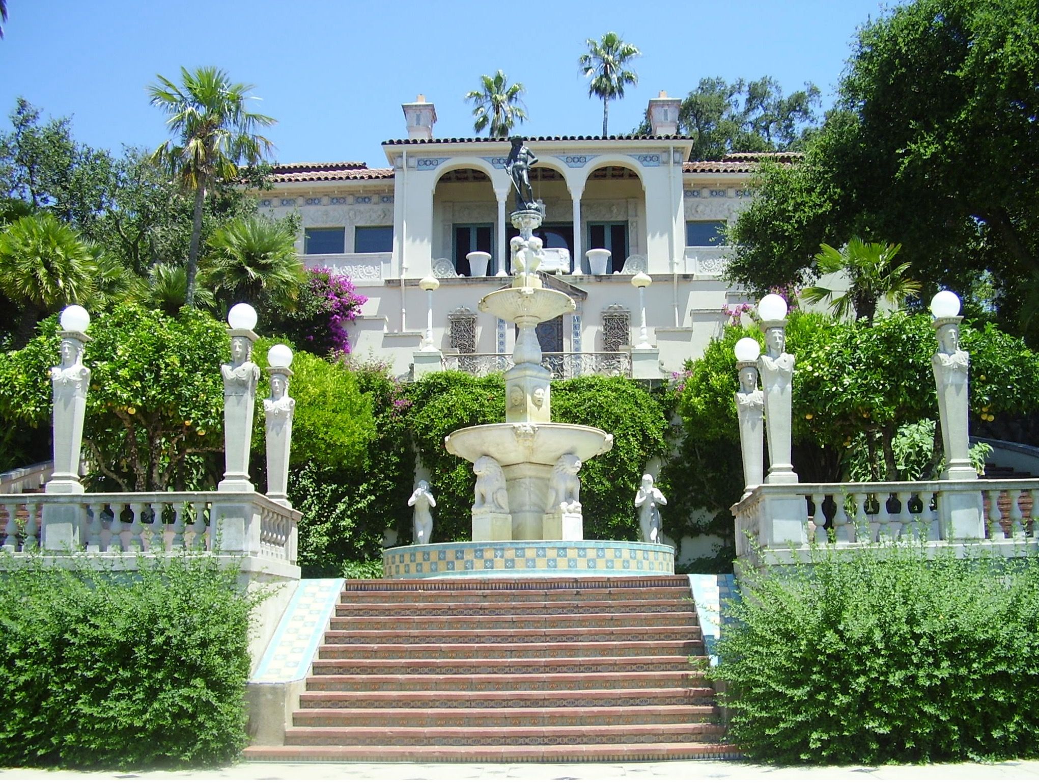 The front of the Hearst Castle with steps leading to a garden fountain and the castle in the background.