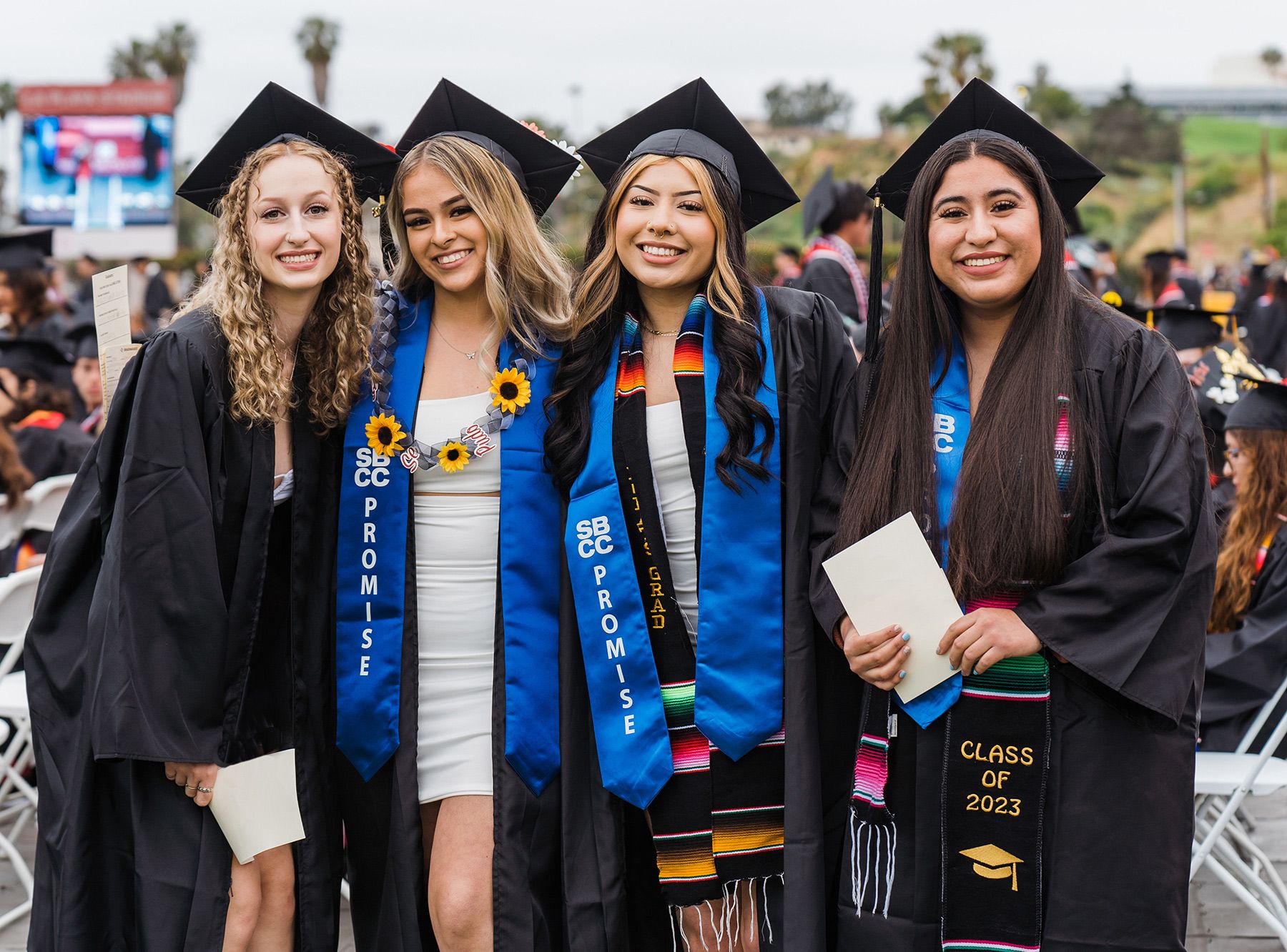 Four female college graduates pose for a photo in their caps and gowns.