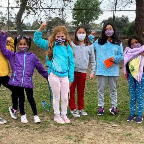Girls outside in the wilderness wiht masks on doing fist pumps
