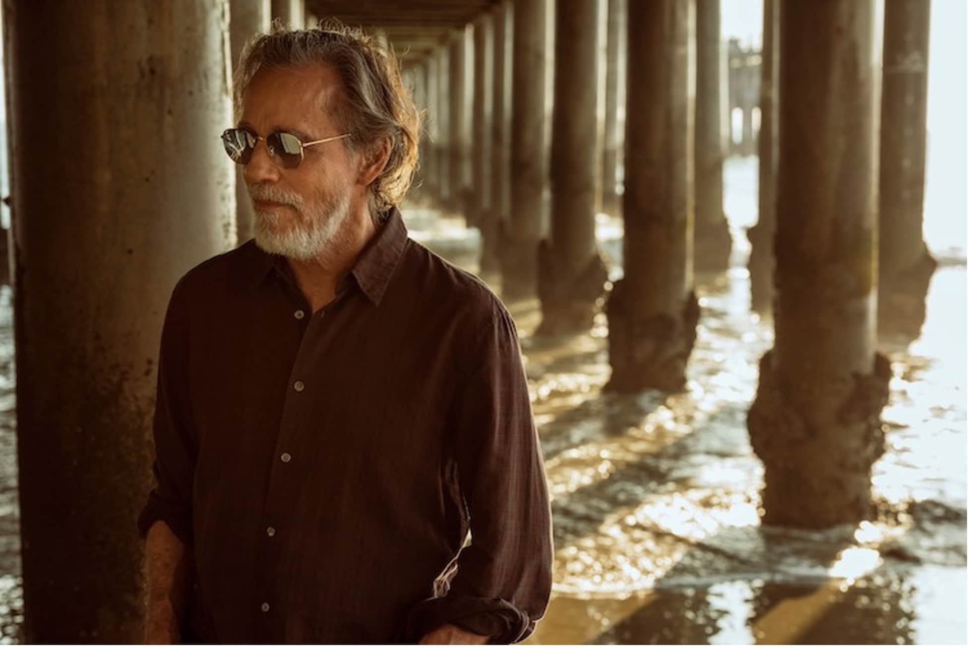 Jackson Brown standing on a beach under a pier