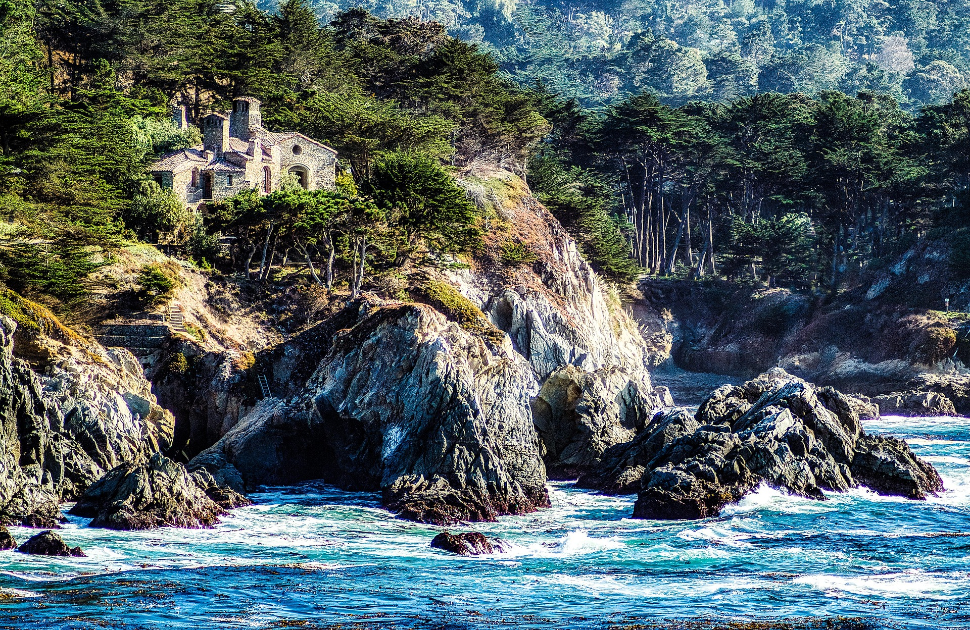 A stone facade home iabove a rocky beach in Carmel, CA.