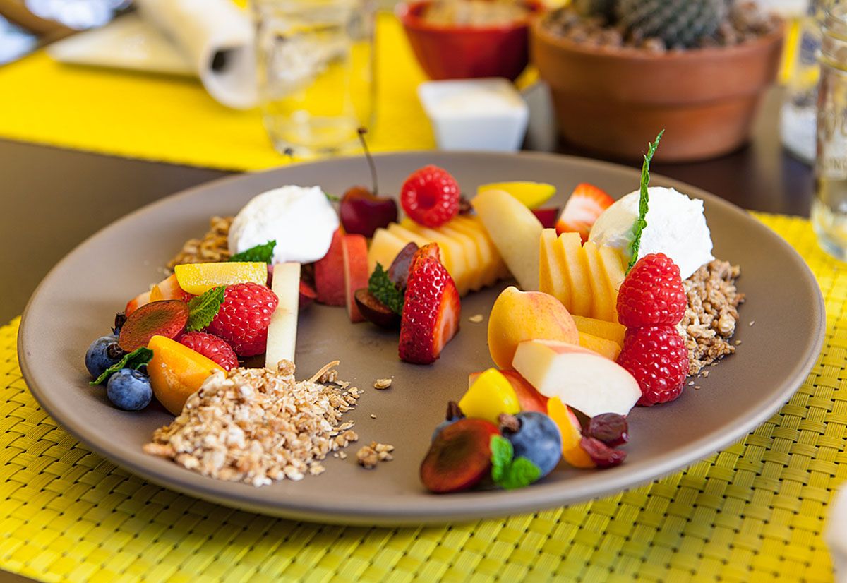 Colorful array of fresh fruit and grains on a large plate and yellow tablecloth