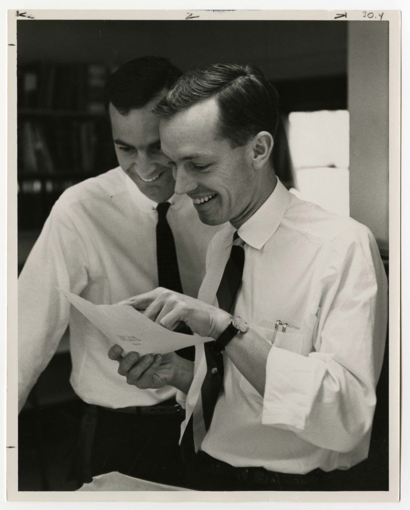 A black and white photo of architects John Kelsey and Thornton Ladd looking at a document