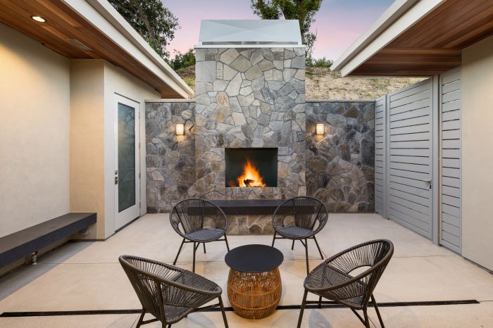 Intimate courtyard of an upscale Ventura home, with seating and a lighted fireplace set in a stone wall.
