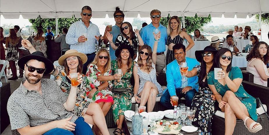 A group of happy people holding up their drinks at the Santa Barbara Polo and Racquet Club.