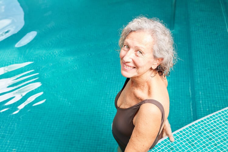 Senior woman ready to jump in the pool for swimming exercises.