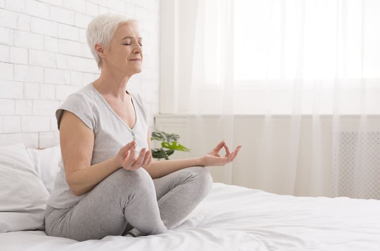Senior woman doing lotus pose during meditation.