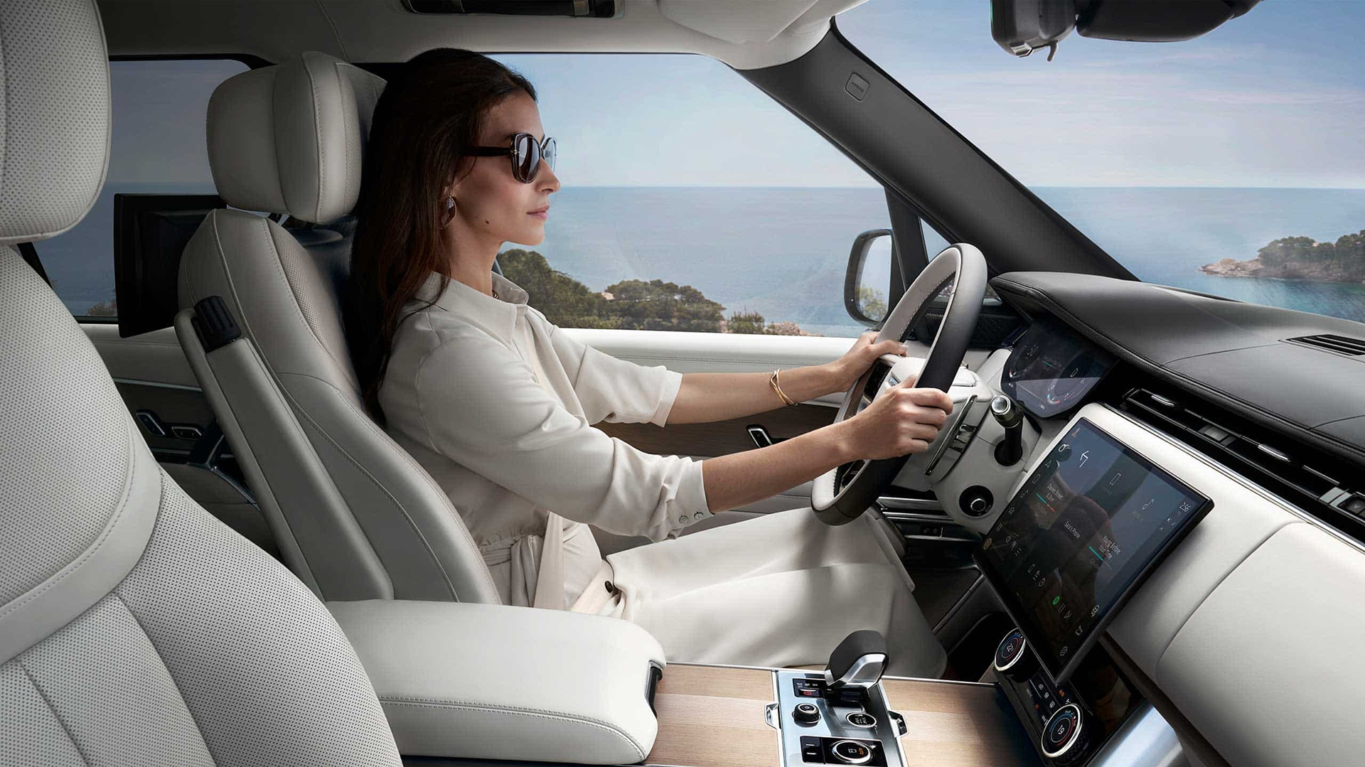 A woman driving a Range Rover along the coast