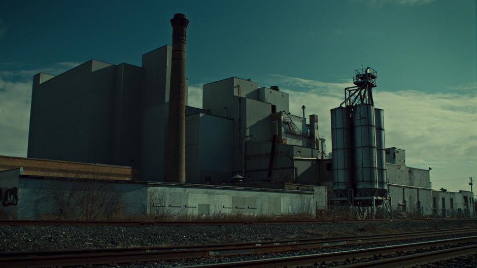 Establishing shot of the factory across from some train tracks.