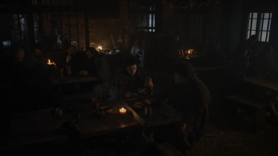 Arya continues to scarf down her meal while talking with Hot Pie.