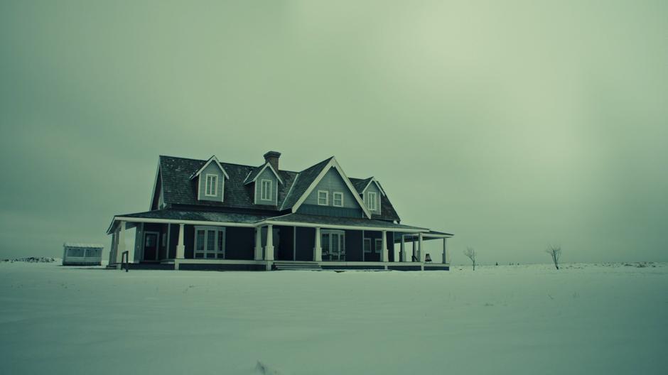 Establishing shot of the mansion surrounded by snow during the day.