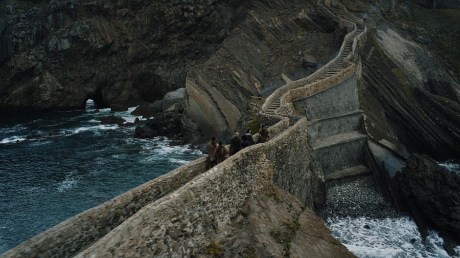 Tyrion, Missandei, Jon, Davos, and two Dothraki walk up the path towards the castle.