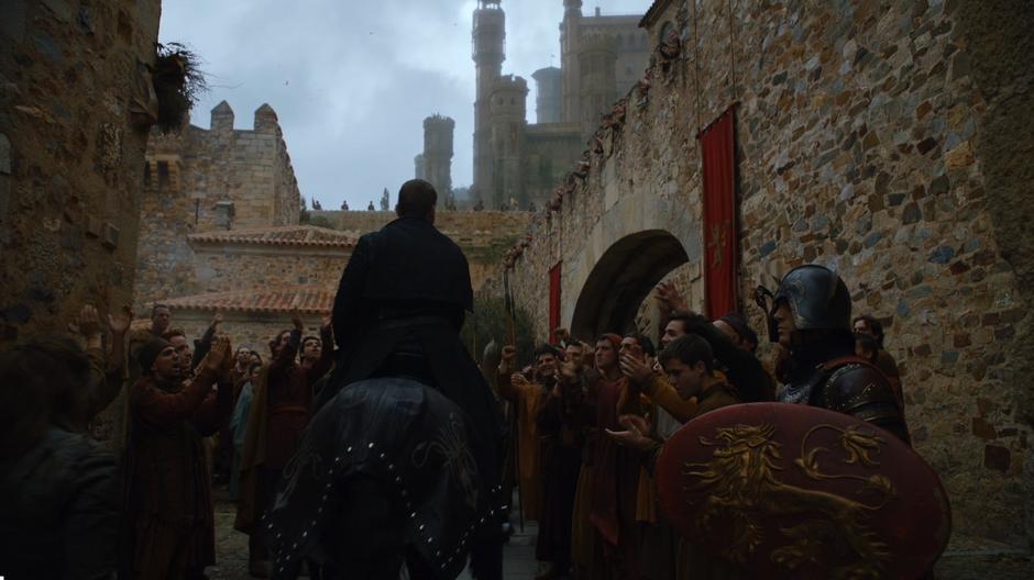Euron rides his horse through another group of cheering townsfolk.