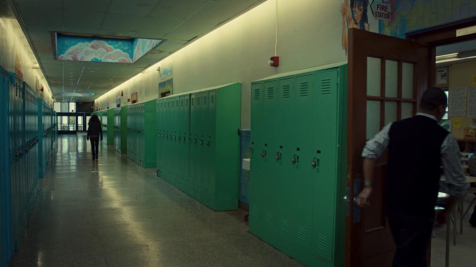 Sarah walks down the hallway away from the exam room while the proctor closes the door to the exam room.