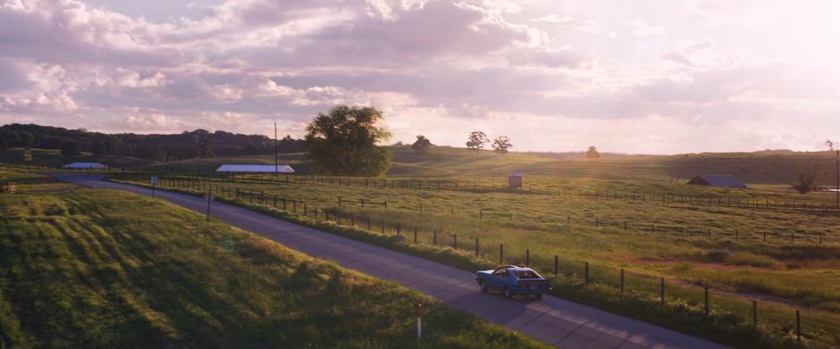 The car continues down the road into the distance.