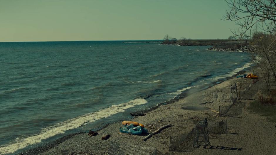 Jonathan lies unconscious on the sand as a large hole in the ground next to him spews smoke.