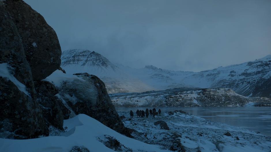 The party walks along the shore of the icy lake.