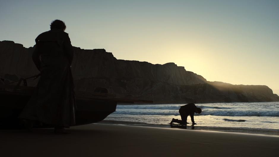 Theon kneels down at the edge of the water after winning the fight.