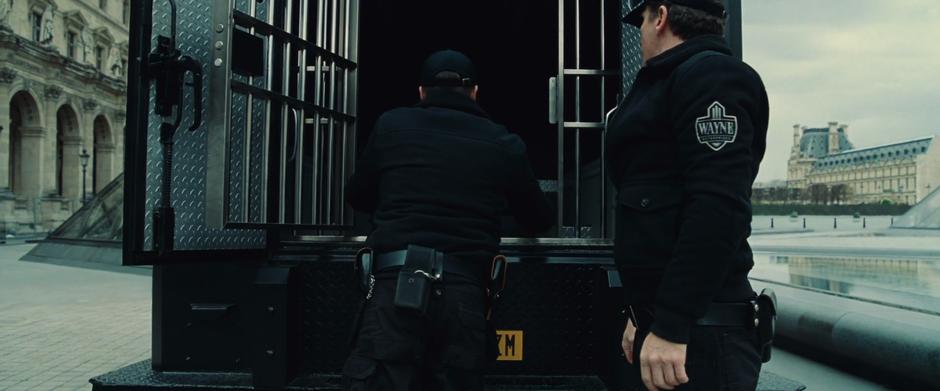 Two armored car drivers pull the delivery out of the truck.