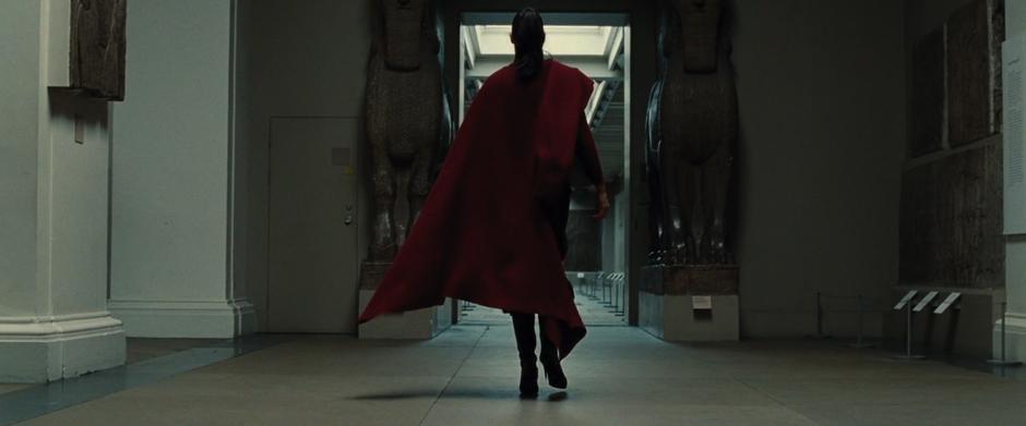 Diana walks away from the camera between two statues in the museum.