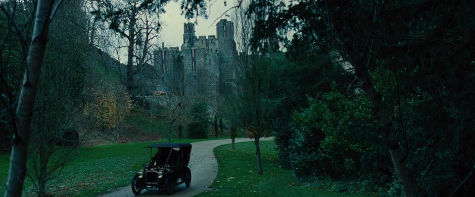 A car drives down the road away from the castle.