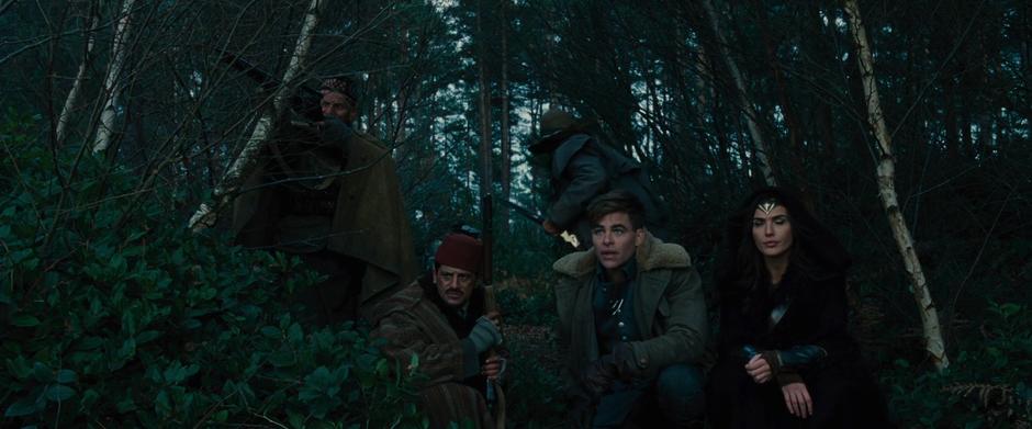 The team crouches down at the edge of the woods as Charlie checks out the castle through his rifle's scope.