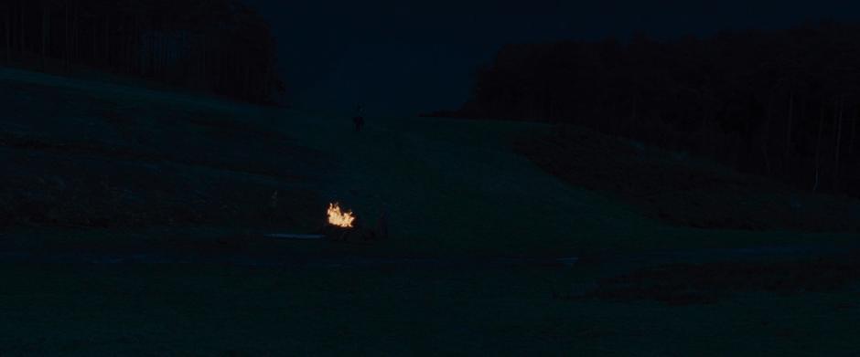 Diana rides up the hill past the fire that the Chief, Charlie, and Sameer lit for her.