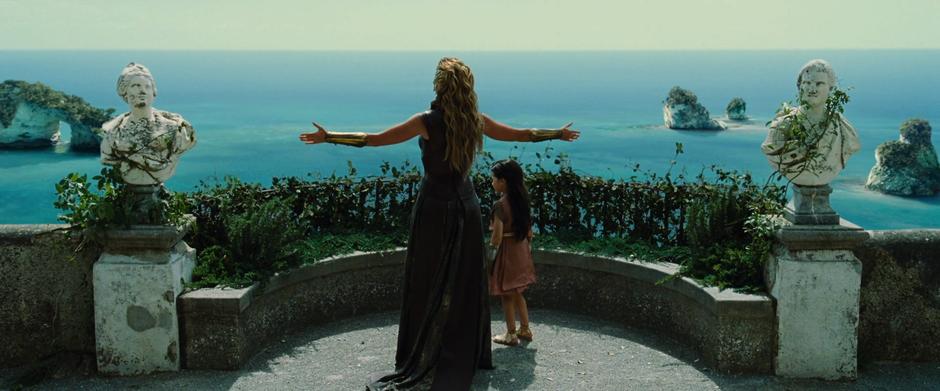 Hippolyta spreads her arms out to the ocean and everything around them to young Diana.