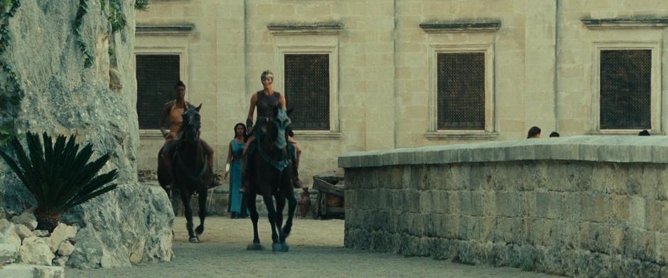 Hippolyta and one of the other Amazons ride down the street after Diana.