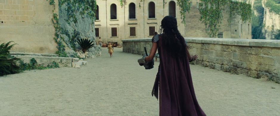 One of the Amazons attempts to stop Diana who is running towards her down the street.