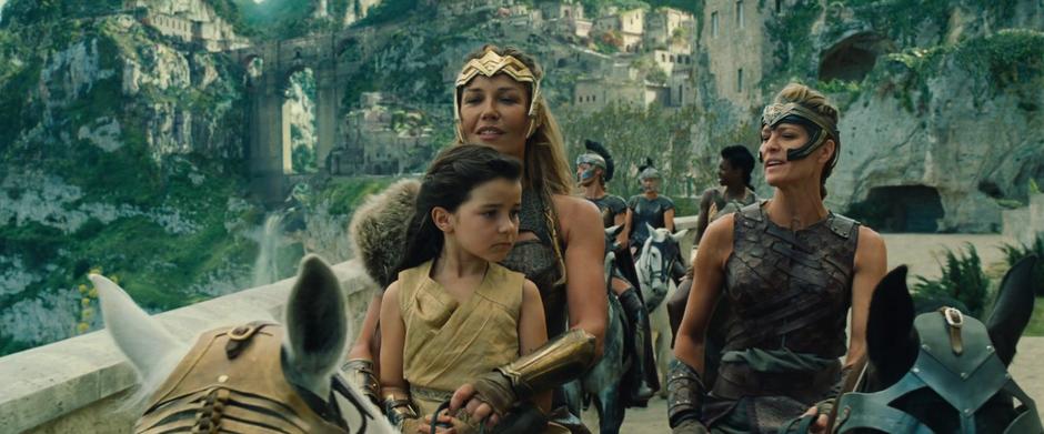 Antiope chats with young Diana as Diana rides on a horse with her mother.