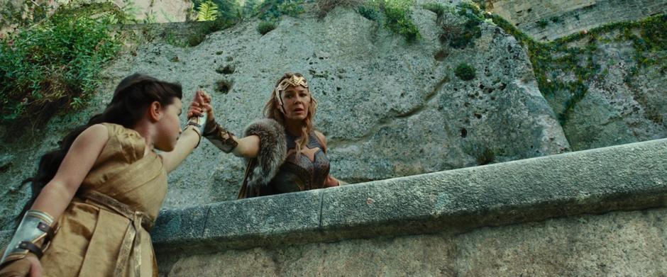 Hippolyta holds young Diana by the arm after stopping her from jumping over the edge.