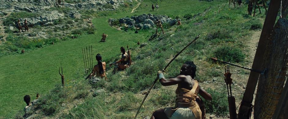 A Amazon warrior ducks as Diana shoots an arrow in her direction.