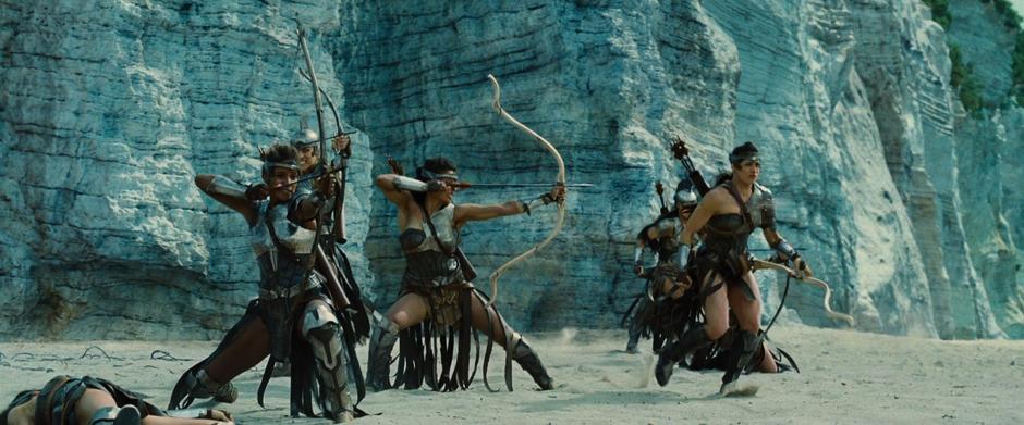 Several Amazons shoot arrows at the German soldiers after landing on the beach.