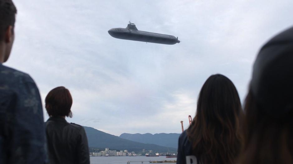 People watch as Kara lifts the submarine high into the sky.